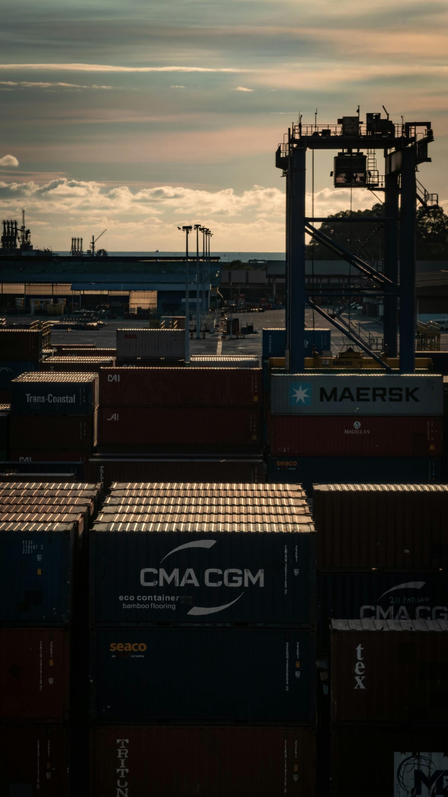 Stacked shipping containers at a Malaysian port during sunset, showcasing global trade.
